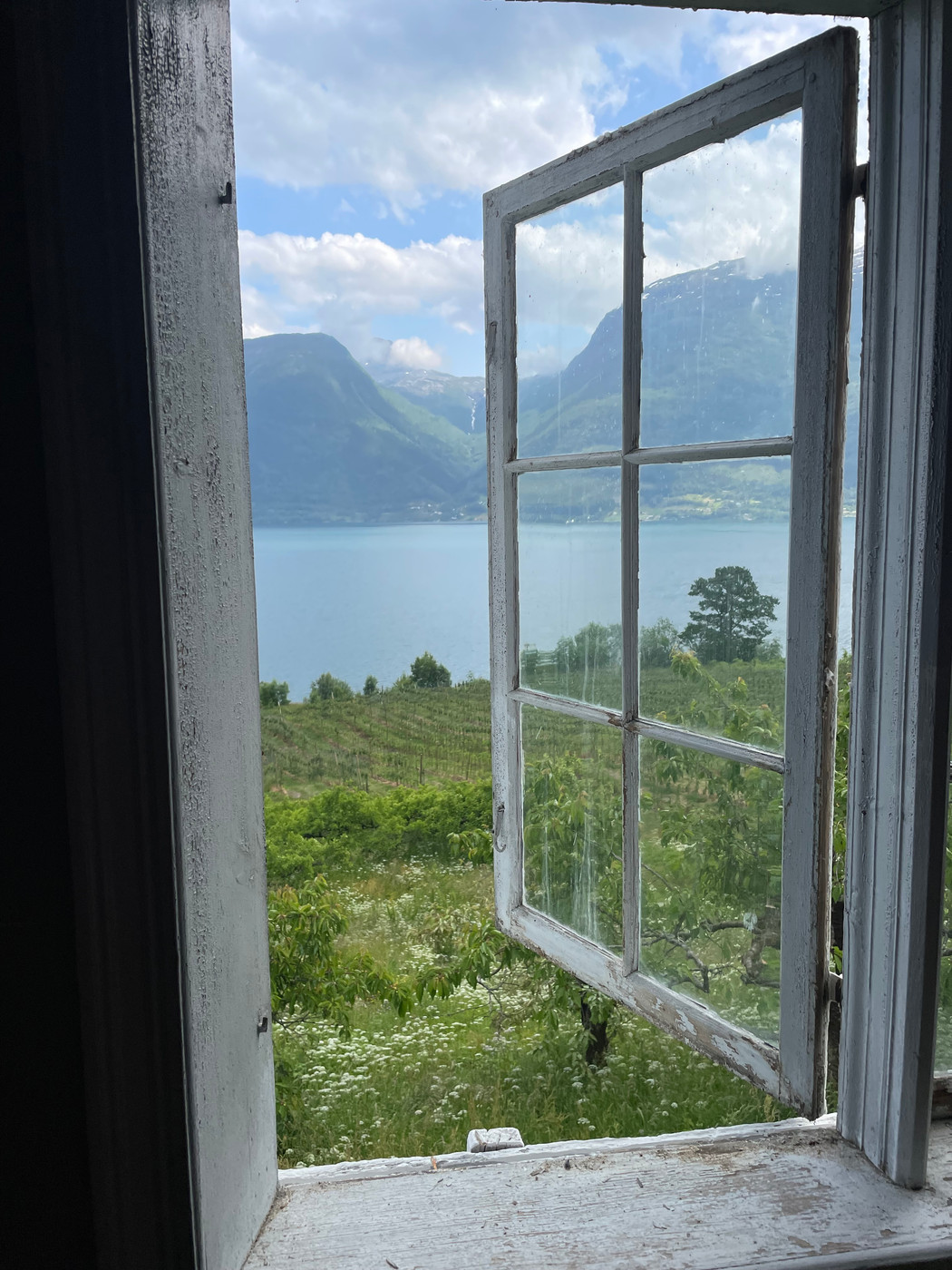 Utsikt til fjordlandskap sett fra åpent vindu.