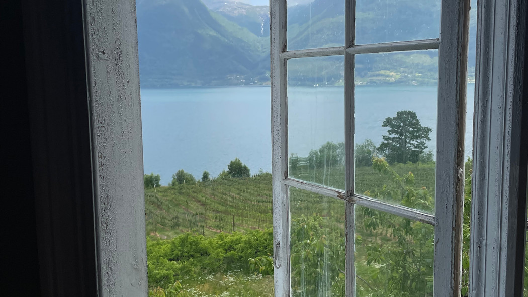 Utsikt til fjordlandskap sett fra åpent vindu.